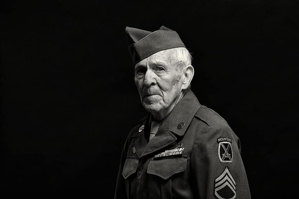 Black-and-white portrait of a 10th Mountain Division WWII veteran in his original wartime uniform, division patch visible on the sleeve.